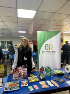 Representante de BO Packaging junto al pendón "Envasamos tus ideas" y muestras de envases en el evento de inocuidad de DailyFoods